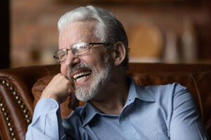 Older man laughing while sitting in a chair