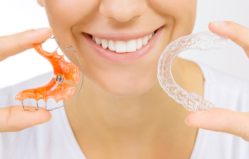 Patient holding their Invisalign aligner and a retainer