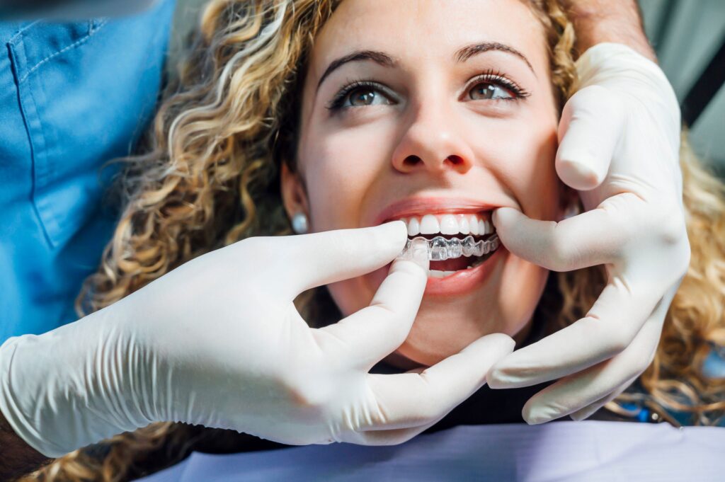 Dentist placing Invisalign over woman's upper arch